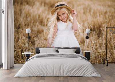 beautiful little girl in a hat with blond hair on a wheat field background Wall mural