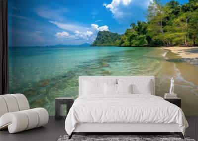 Crystal-clear water at a tropical beach with rocky shoreline under a bright blue sky and lush greenery in the background Wall mural