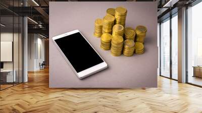 Online shopping concept. white smartphone, and coins on a gray background Wall mural