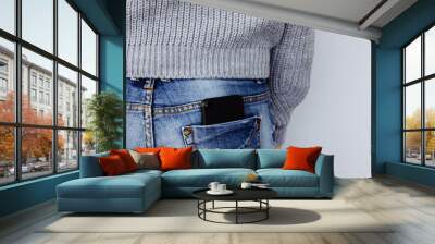 A mobile phone in the back pocket of a jeans on a girl in casual clothes. Wall mural