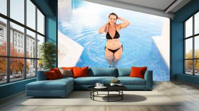 A cheerful  woman in the pool on a sunny day. Beautiful woman having fun in the pool. summer vacation Wall mural