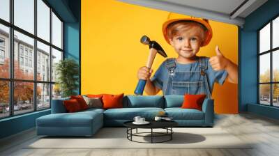 Little boy in a construction helmet and with a hammer on a yellow background Wall mural