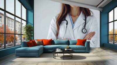 Capture a close-up photo of a friendly, confident female doctor with her arms crossed, smiling warmly at the camera against a clean white background. Highlight her positive demeano Wall mural