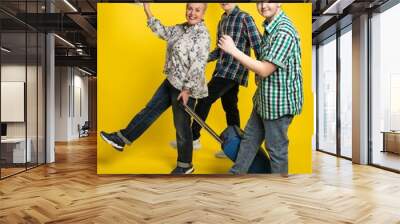 family with a suitcase. Studio colored background. blue yellow. Cheerful, plump woman and two guys, son go on vacation. lady holding money, laughing. body positivity plus size Wall mural