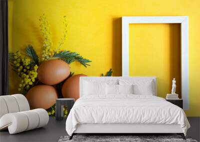 Brown chicken eggs on a yellow background and a branch of mimosa with shadows. Easter spring background. Copy space Wall mural