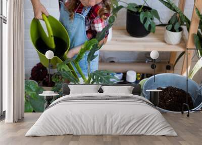 Girl transplants a potted houseplant philodendron into a new soil with drainage. Potted plant care, watering, fertilizing, hand sprinkle the mixture with a scoop and tamp it in a pot. Hobby and enviro Wall mural