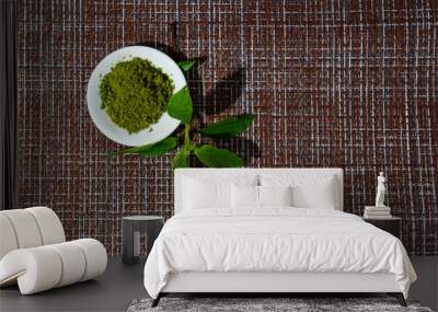 Japanese matcha green tea is poured into a white mug and on a white saucer in powder. Tea set on a textured napkin of natural flowers, decorated with a branch of green leaves. Background with space fo Wall mural