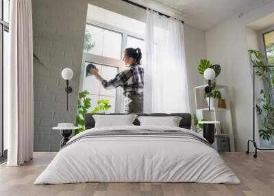 Woman manually washes the window of the house with a rag with spray cleaner and mop inside the interior with white curtains. Restoring order and cleanliness in the spring, cleaning servise Wall mural