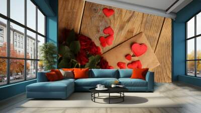 A bouquet of red roses and a letter with hearts on a wooden background. Picture for Valentine's Day. The concept of gifts and lovers. High-quality photography Wall mural