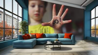 3 years old boy making a stop signal with his hand. Word No writing on palm. Safety and violence concept Wall mural