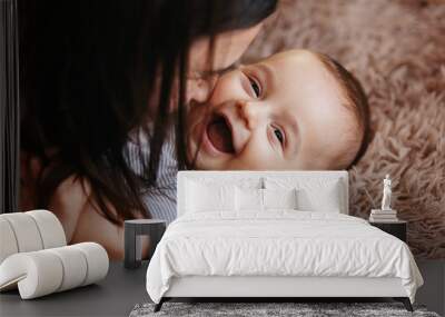 Happy cheerful family. Mother and baby kissing, laughing and hugging. Home happiness Wall mural