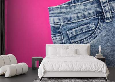 Blue jeans - front pockets close-up on a bright pink background. The concept of fashion, style, universal clothing. Place for text, flat lay, minimalism. Wall mural