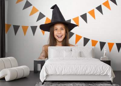 Funny funny girl in Hat and witch costume for Halloween shows fingers in the top cool. Wall mural