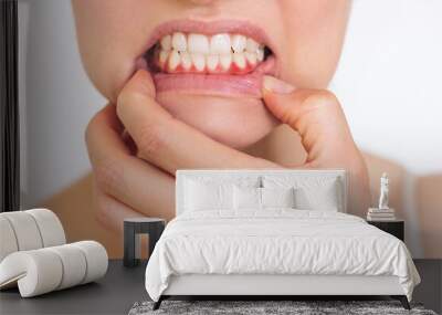 a close-up photo of a young woman who shows inflamed red bleeding gums isolated on a white background. Dentistry. Gum disease Wall mural