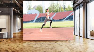 Beautiful athletic girl running around the stadium Wall mural