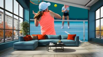 A girl plays tennis on a court with a hard blue surface on a summer sunny day Wall mural