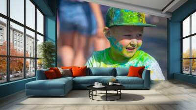 Little boy sprinkled with multi-colored powder at the Festival of colors. Wall mural