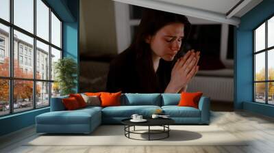 Teenager praying to God at night in apartment Wall mural