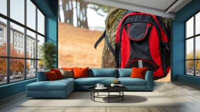 Black and red travel backpack hanging on a tree. Wall mural