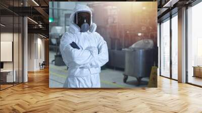 man in chemical protection clothes and toned mask in a factory against the background of an industrial workshop looking into the frame.  Wall mural