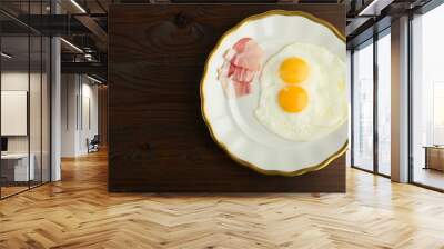 two fried eggs is on the plate on dark wooden background Wall mural