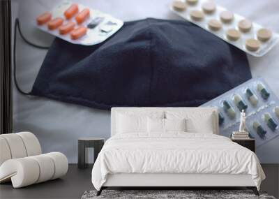  An expanded black protective mask lies on fabric napkins next to tablets and an antiseptic. Fighting COVID-19 Wall mural