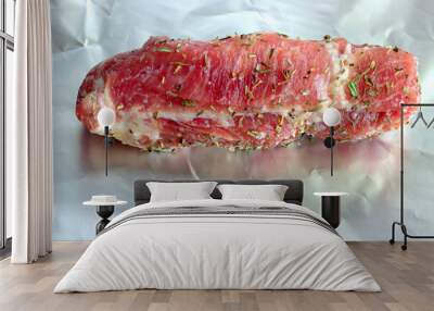 A piece of bright red pork neck seasoned with dried herbs and salt on a brightly reflective foil Wall mural