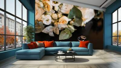 wedding rings and bridal bouquet lie on a dark background Wall mural