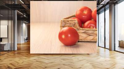 red ripe tomatoes in a basket on a light background Wall mural