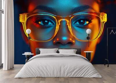 A close-up of a woman with vibrant yellow glasses accentuated by colorful lighting in a dramatic portrait Wall mural