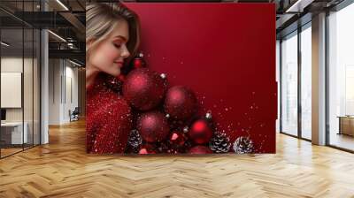 A young woman rests beside festive decorations on a vibrant red background during the holiday season Wall mural