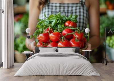 Freshly harvested tomatoes and basil displayed in a bowl by a person wearing a checked apron in a vibrant market setting Wall mural