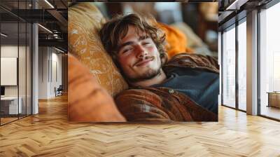 Young man relaxing on a cozy couch surrounded by warm colors in a rustic living room, displaying a serene expression and casual attire Wall mural