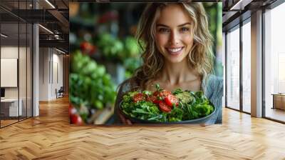 Young woman smiling while holding a bowl of fresh salad at a vibrant outdoor market on a sunny day Wall mural