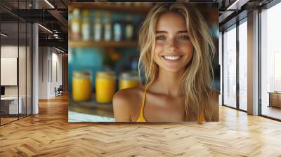 Young woman with a radiant smile poses in a beachside café during a sunny day while colorful drinks are visible in the background Wall mural