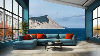 rocky sea shore view, blue water and parachute Wall mural