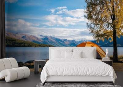 A vibrant orange camping tent rests by a tranquil lake, surrounded by mountains, as a person captures the serene autumn landscape from inside the tent Wall mural