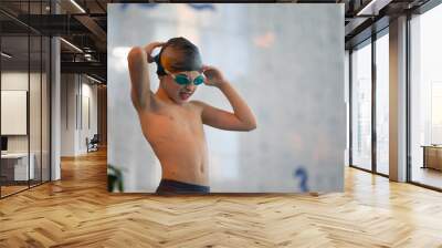 Boy in a swimming cap and swimming goggles in the pool. The child is engaged in the swimming section. Wall mural