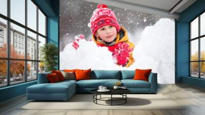 Child in winter. A happy boy in bright clothes plays in the snow. Wall mural