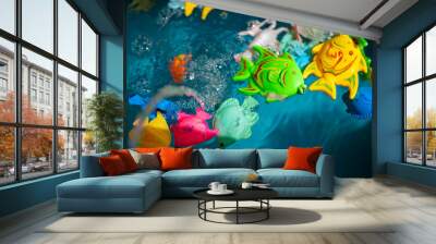 Toy colorful fish in blue water. Wall mural