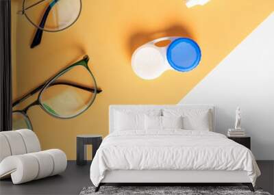 Optical glasses, contact lenses and eye drops on a yellow and white background, top view, flat lay. Wall mural