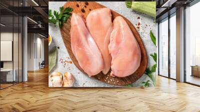 Raw uncooked chicken fillet on a wooden cutting board top view. Raw poultry fillet on a grey concrete background. Wall mural