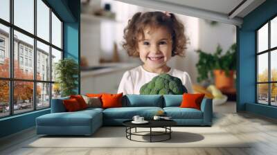 Portrait of a cute child girl with broccoli in her hands in the kitchen at home Wall mural