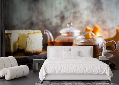 A Cup of tea on a saucer, a kettle of hot tea and a cheesecake on a platter on a grey vintage background Wall mural