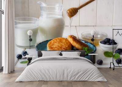 Sweet breakfast: sweet pancakes with honey on a beautiful blue plate on a white table. Cottage cheese with honey Wall mural