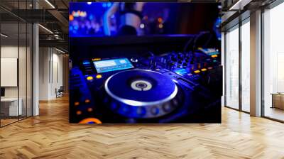 Disc Jockey mixing deck and turntables at night with colourful illuminated controls for mixing music for a party or disco Wall mural