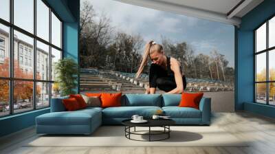 girl tying shoelaces on sneakers, jogging in the stadium Wall mural