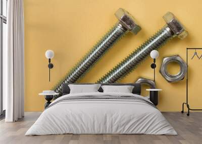 Two shiny metal bolts and two nuts on a yellow background. Wall mural