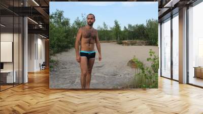 A man in swimming trunks in nature Wall mural