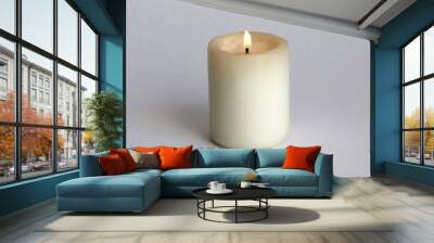 The candle burns brightly on a white background. Wall mural